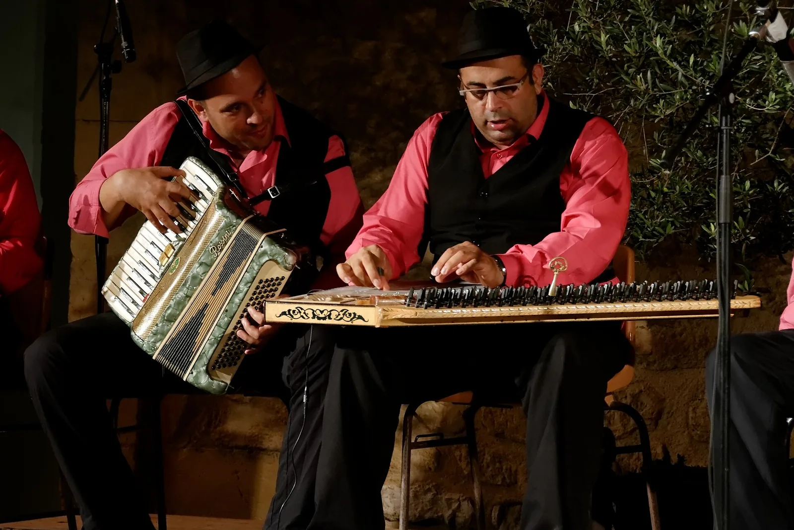Two musicians from the Ahırkapı Roman Orchestra of Istanbul play a qanun and an accordion on a dimly lit stage, photographed at a festival in France in 2014.
